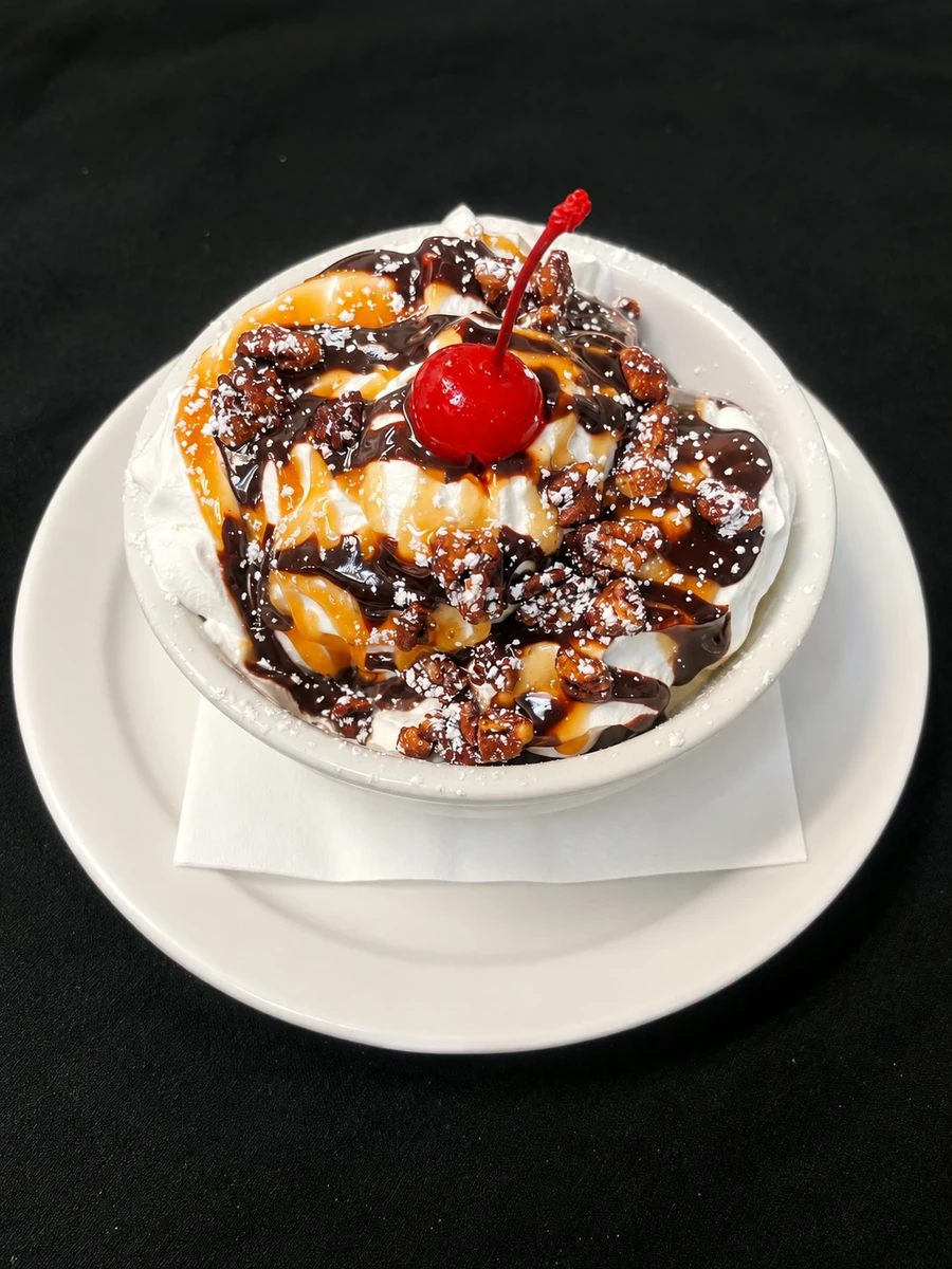 Ice cream sundae with caramel, chocolate, candied pecans and a cherry